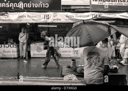 PHUKET, Tailandia 3 Ottobre 2011: un mercato fornitore di stallo sta dietro un tavolo offerte durante il Phuket Festival vegetariano. Foto Stock