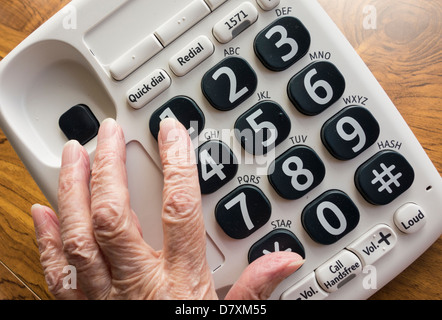 Signora anziana con ipovedenti premendo il numero 1 sul grande pulsante telefono Foto Stock