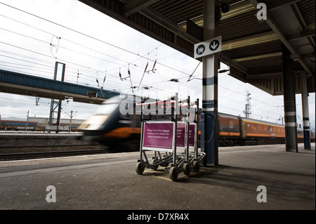 Un treno ad alta velocità che passa attraverso una stazione ferroviaria, UK. Foto Stock