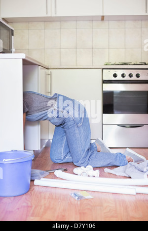 Donna di lavorare sotto il lavello da cucina Foto Stock