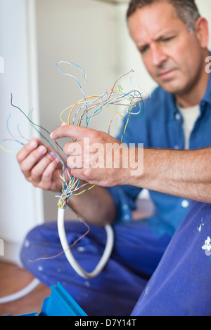 Elettricista esaminando i fili in cucina Foto Stock