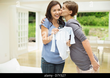 Donna incinta dando amico vestiti del bambino Foto Stock