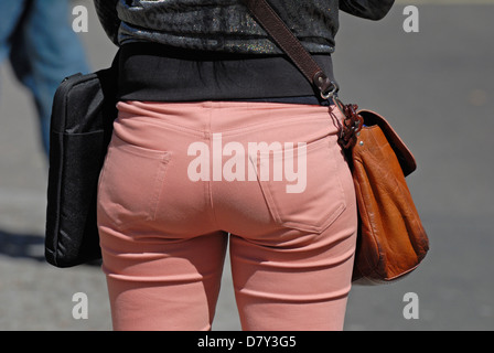 Londra, Inghilterra, Regno Unito. Donna che indossa stretti, rosa, indebolita di jeans e trasporto borsa in pelle Foto Stock