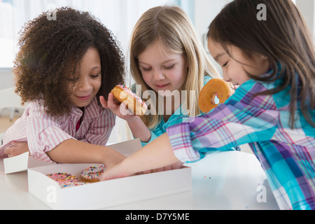 Le ragazze di mangiare le ciambelle insieme in cucina Foto Stock