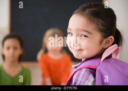 Ragazza sorridente guardando sopra la sua spalla Foto Stock