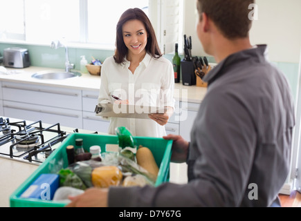 La donna la firma per la consegna in cucina Foto Stock