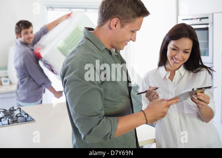 La donna la firma per la consegna in cucina Foto Stock