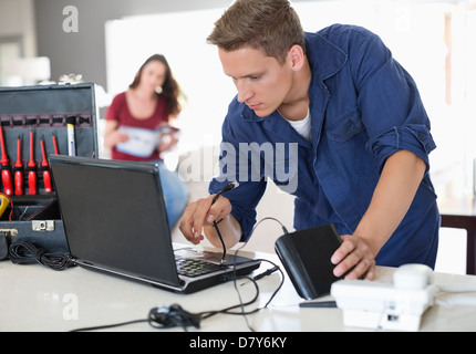 Elettricista utilizzando laptop in casa Foto Stock