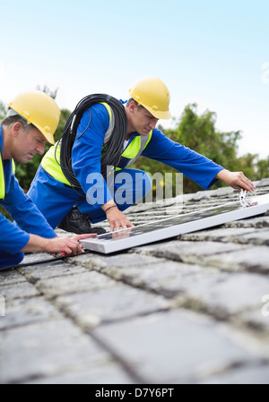 I lavoratori di installare pannelli solari sul tetto Foto Stock