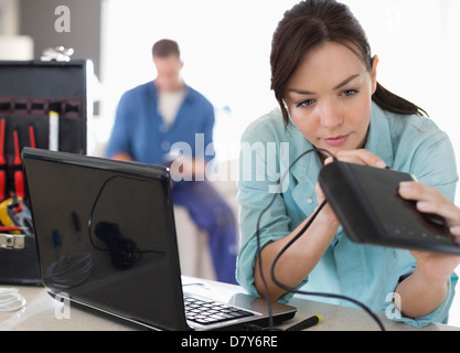 Elettricista femmina lavorando sul computer portatile in casa Foto Stock