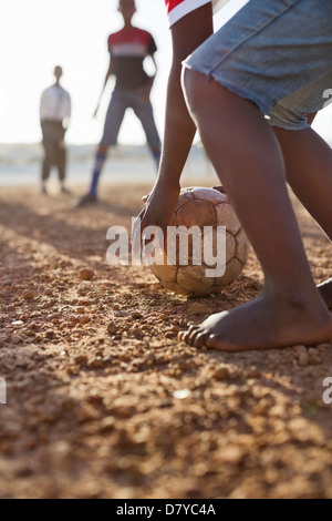 Ragazzi che giocano a calcio insieme nel campo di sporco Foto Stock