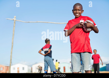 Ragazzo tenendo palla calcio nel campo di sporco Foto Stock