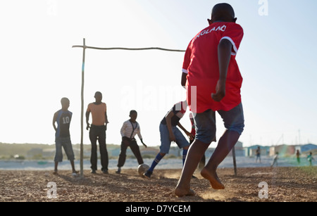 Ragazzi che giocano a calcio insieme nel campo di sporco Foto Stock