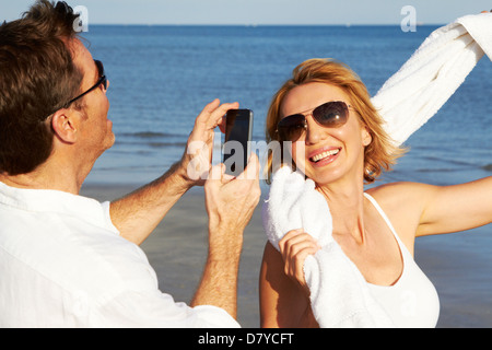 Uomo caucasico scattare foto della ragazza sulla spiaggia Foto Stock