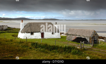 Un tradizionale cottage crofters noto come un blackhouse con tetto di paglia sulla isola di North Uist, Western Isles, Scozia. Foto Stock