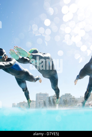 Triatleti tuffarsi in piscina Foto Stock
