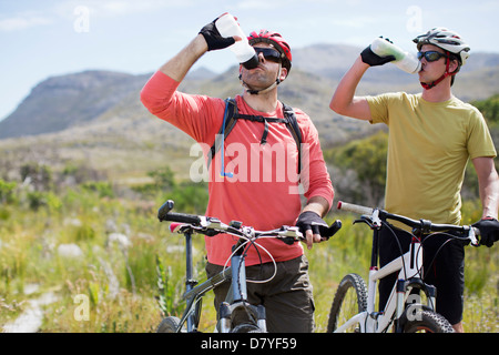 Gli amanti della mountain bike l'acqua di azionamento nel paesaggio rurale Foto Stock