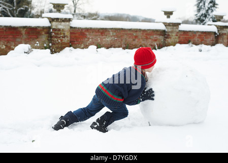 Ragazzo rendendo pupazzo di neve all'aperto Foto Stock