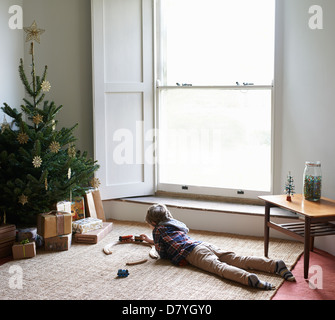 Ragazzo giocando con il treno da albero di Natale Foto Stock