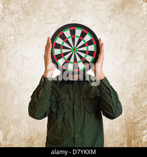 L'uomo azienda dartboard al posto della testa. Foto Stock