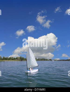 Piccola barca vela sul lago in una bella giornata di sole Foto Stock