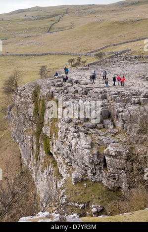 Persone in piedi e camminare sull altopiano di pavimentazione di pietra calcarea, spettacolare caratteristica naturale alla sommità di Malham Cove - Malhamdale, Yorkshire Dales, Inghilterra, Regno Unito. Foto Stock