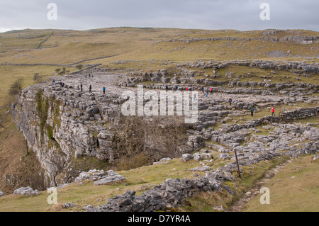 Persone in piedi e camminare sull altopiano di pavimentazione di pietra calcarea, spettacolare caratteristica naturale alla sommità di Malham Cove - Malhamdale, Yorkshire Dales, Inghilterra, Regno Unito. Foto Stock