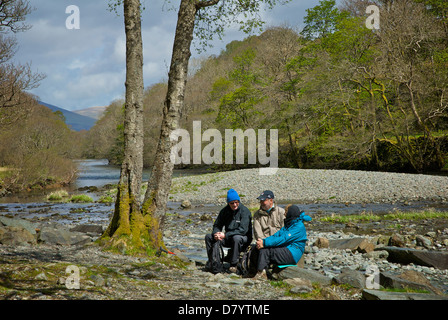 Tre escursionisti in appoggio sul fiume Derwent, in Borrowdale, Parco Nazionale del Distretto dei Laghi, Cumbria, England Regno Unito Foto Stock