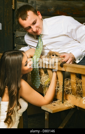 Affascinante la sposa e lo sposo in fienile con coniglio Foto Stock