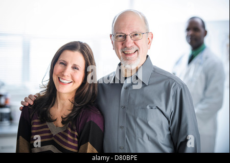 Coppia sorridente in piedi in ambulatorio medico Foto Stock