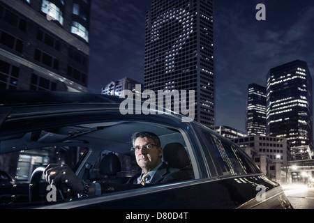 Imprenditore caucasica la guida su una strada di città Foto Stock