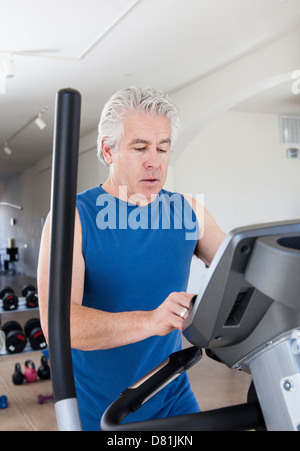 Vecchio uomo ispanico utilizzando macchina ellittica in palestra Foto Stock