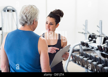 Vecchio uomo ispanico lavora con trainer in palestra Foto Stock