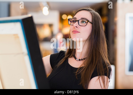 La donna caucasica esaminando dipinto nella galleria d'arte Foto Stock