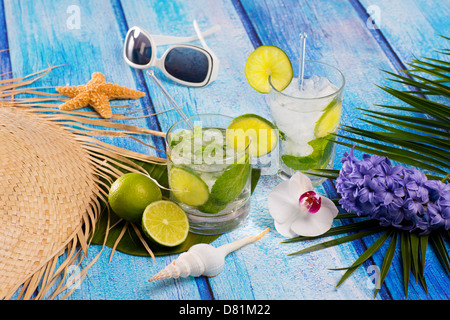 Il Mojito Cubano cocktail tropicale in legno di colore blu con fiori di occhiali da sole e stelle marine Foto Stock