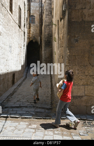 Aleppo Siria. Due bambini percorrendo a piedi una stretta vecchia strada di ciottoli nel centro della città vecchia, un sito Patrimonio Mondiale dell'UNESCO. Foto Stock