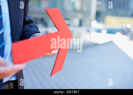 Business man tenendo premuto freccia rossa rivolta verso destra Foto Stock