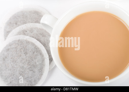 Tazza di tè - semplice tazza di tè con latte e bustine di tè su uno sfondo bianco ripresa dall'alto. Foto Stock