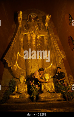 Gotama il Buddha è uno dei 4 Buddha permanente all'interno del tempio di Ananda,persone stanno mettendo la foglia oro sulla statua di Buddha Foto Stock