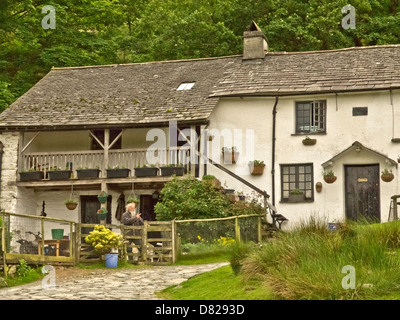 Lake District. Un tipico rurale casa pastorale con un vecchio uomo di fronte ad essa, Tilberthwaite, Cumbria, Regno Unito, Foto Stock