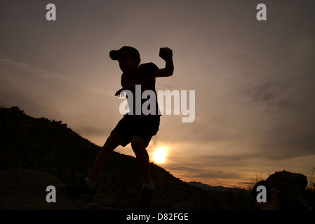 Boys jump massi durante le escursioni ai piedi delle colline di Santa Catalina Mountains, Deserto Sonoran, Catalina, Arizona, Stati Uniti. Foto Stock