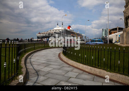 Liverpool, Regno Unito il 17 maggio 2013. La nave da crociera il terminale dove il passeggero luixury nave registrata in Bermuda Liner RMS Queen Mary 2 ormeggiato sulla sua visita alla città. Il Liverpool Cruise Terminal è un 350-metro-lunga struttura galleggiante situato sul fiume Mersey consentendo grandi navi da crociera per visitare senza inserire il dock chiuso o sistema di ormeggio a metà fiume e i passeggeri di gara a terra. Il terminale è stato ufficialmente inaugurato il 21 Settembre 2007 da Sua Altezza Reale il Duca di Kent quando la Queen Elizabeth 2 ormeggiate presso il terminale. Foto Stock