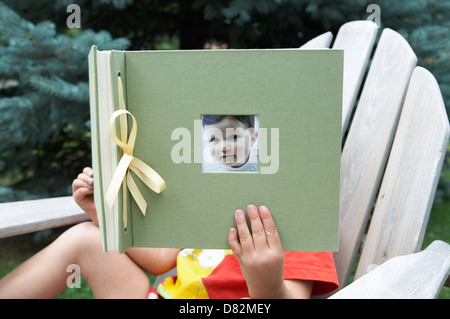 Bambino azienda album di foto con il suo bambino foto sulla parte anteriore Foto Stock