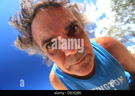 Un malato di mente l uomo nella sua degli anni cinquanta guardando verso il basso su una telecamera blue sky sfondo BDA ORIZZONTALE Foto Stock