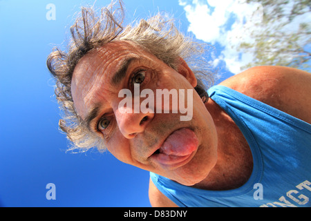 Un malato di mente l uomo nella sua degli anni cinquanta guardando verso il basso su una telecamera blue sky sfondo BDA ORIZZONTALE Foto Stock