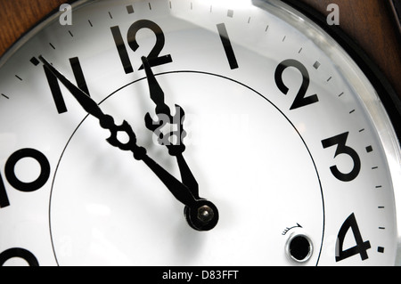 Orologio da parete che mostra cinque minuti a dodici Closeup di un quadrante Foto Stock