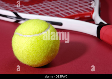 Tennis ball and tennis racket isolated on red background Foto Stock