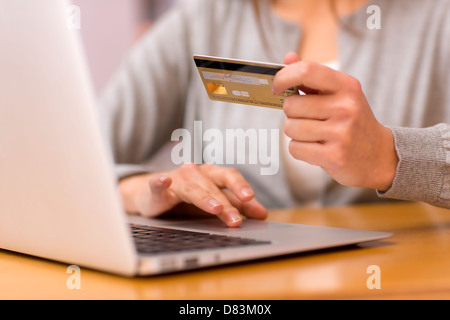 Femmina di fare shopping su internet con il suo computer portatile Foto Stock