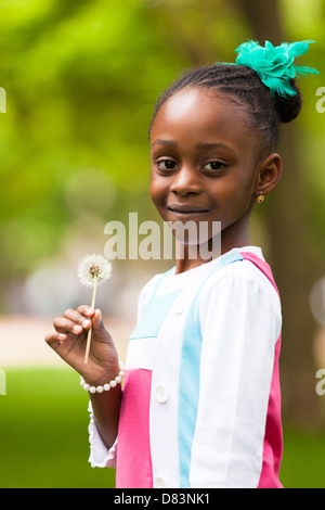 Outdoor ritratto di un simpatico giovane nero ragazza con un fiore di tarassaco - popolo africano Foto Stock