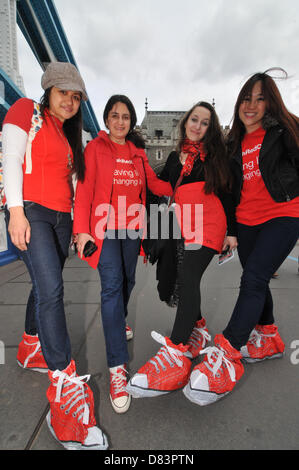 Il Tower Bridge di Londra, Regno Unito. Il 18 maggio 2013. Colore rosso pattino a piedi in aiuto della Croce Rossa di settimana, un ente di beneficenza a piedi attraverso il centro di Londra, con il Walkers indossando scarpe rosso o scivolare su di coperchi di colore rosso. Credito: Matteo Chattle / Alamy Live News Foto Stock